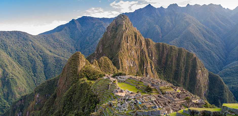 A panoramic photo of Machu Picchu, taken from a hill overlooking the citadel. Huayna Picchu and other Andean mountains are in the background