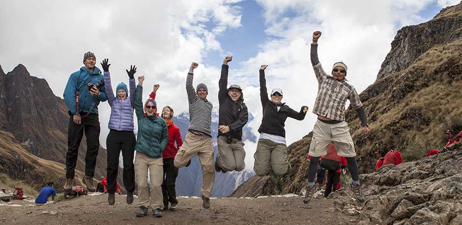 A photograph of hikers on an Inca Trail tour jumping in the air with their guide