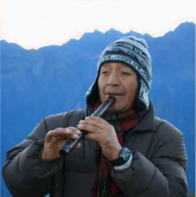 A Peruvian Inca Trail guide plays a flute, with mountains in the background