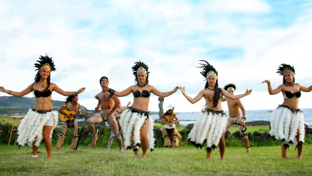 polynesian performers dancing in a grass field on a sunny, cloudy day in Easter Island