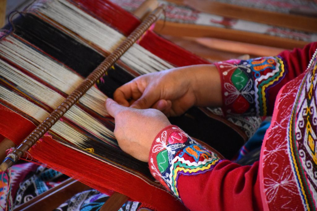 Craft seller in Peru weaving traditional colorful textiles