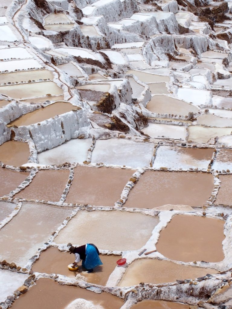 Lady mining from salt pans in Maras, Peru