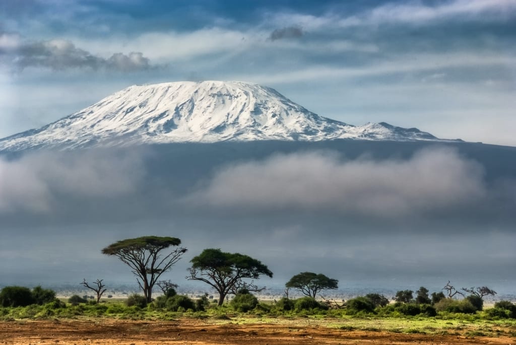 Snow-capped summit of Mount Kilimanjaro peeking through clouds