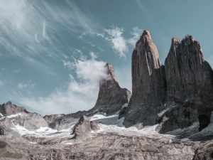 A desaturated photograph of the Torres del Paine, the three granite towers of the Paine Massif in Patagonia. The steep towers are a highlight for many hikers on the W Trek