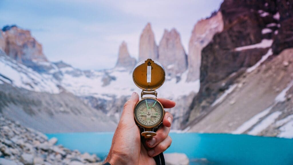 Hand holding compass facing Torres del Paine towers on W Trek