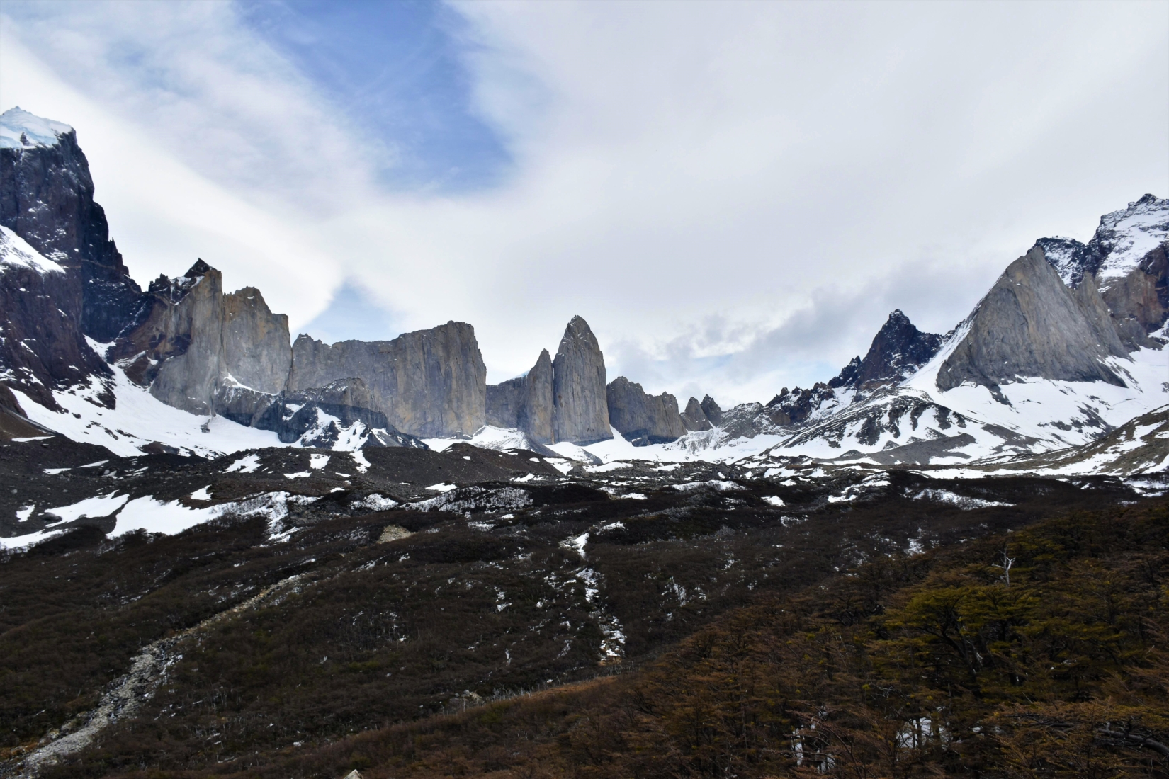 Snow-covered Chilean mountain range surrounding green valley in Patagonia