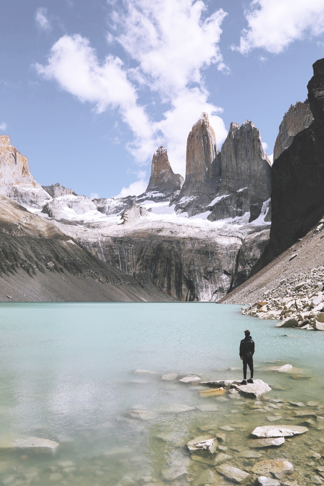 A photograph of Torres del Paine (three granite towers), with a hiker and the lagoon in the foreground