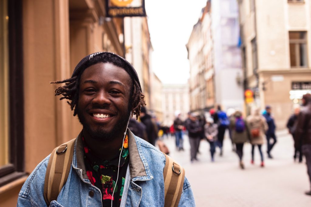 Smiling young man with a backpack traveling in a city.