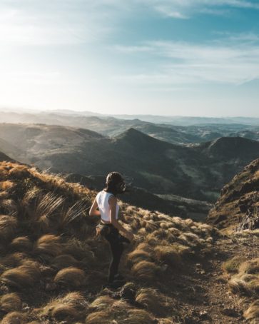 Woman trail hiking alone down a mountain on a blue sky day.