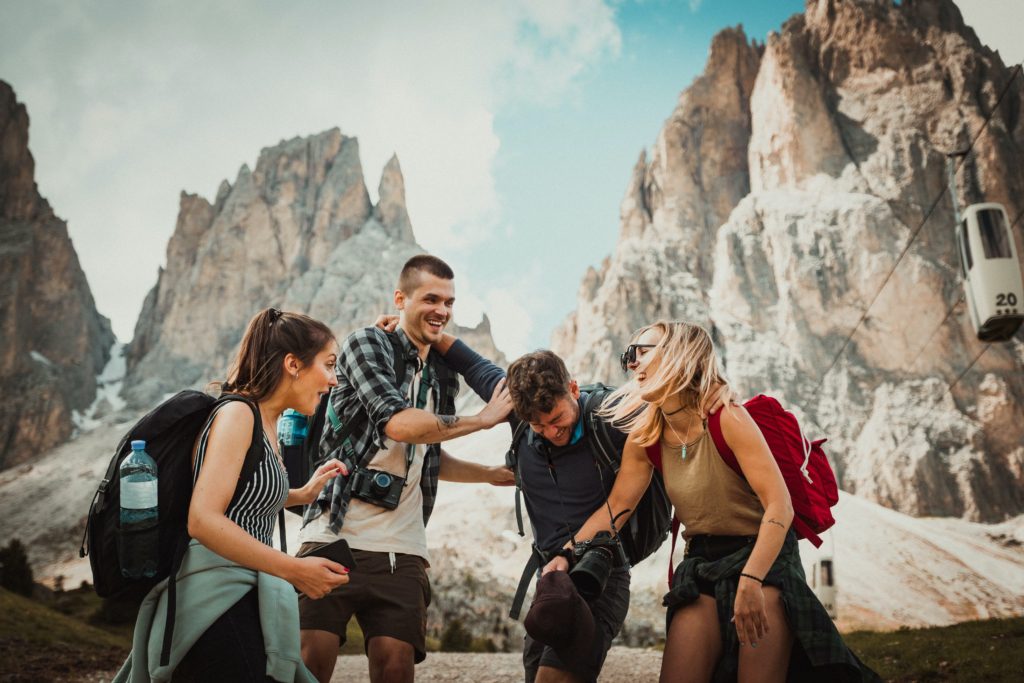 Group of friends traveling together and laughing in front of stone mountains.