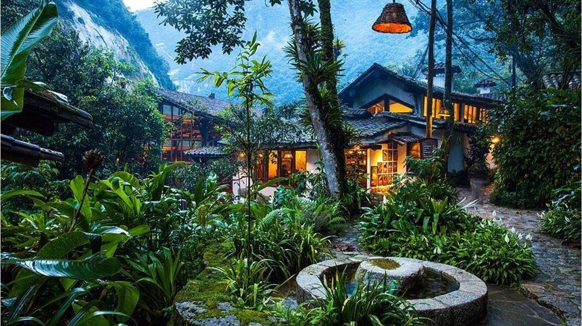 A photograph of the Inkaterra Machu Picchu Pueblo Resort in Aguas Calientes, Peru taken in the early evening. The photograph showcases the unique location and beautiful forest setting. Many people who are hiking the Inca Trail to Machu Picchu will stay here as part of The Explorer's Passage 5 Star Hotel package option