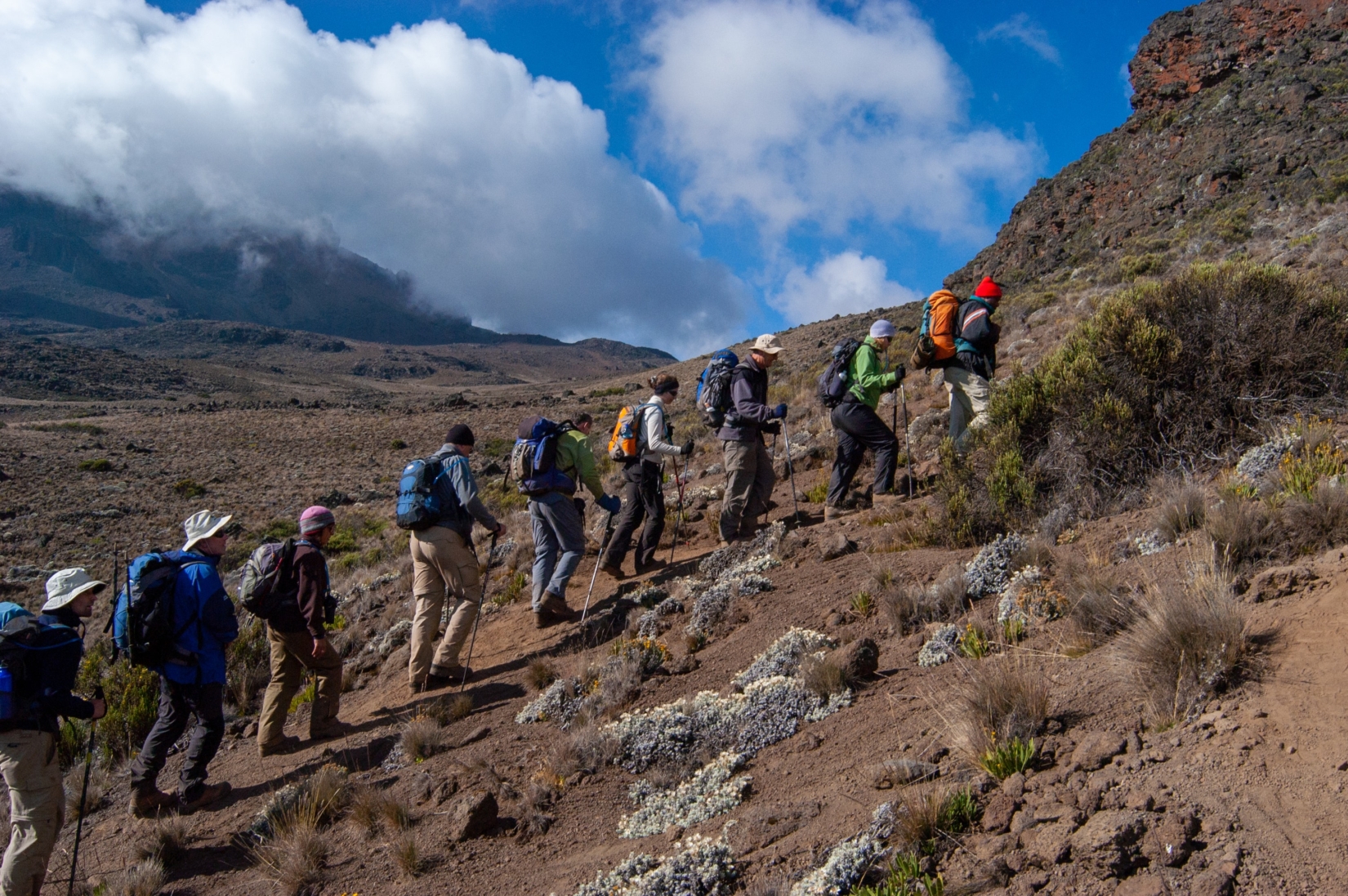 Line of hikers walking uphill in the mountains on Rongai route
