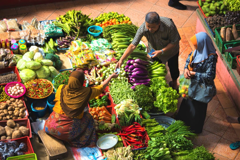A woman selling fresh vegetables to a customer in a local sustainable food market