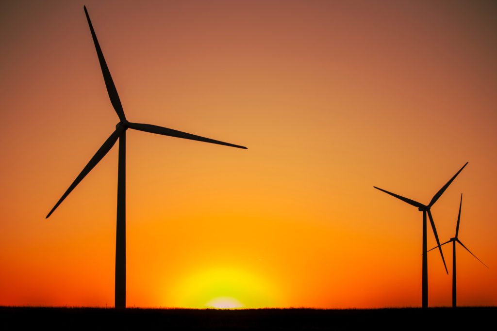 A sunset or sunrise by a field of wind turbines