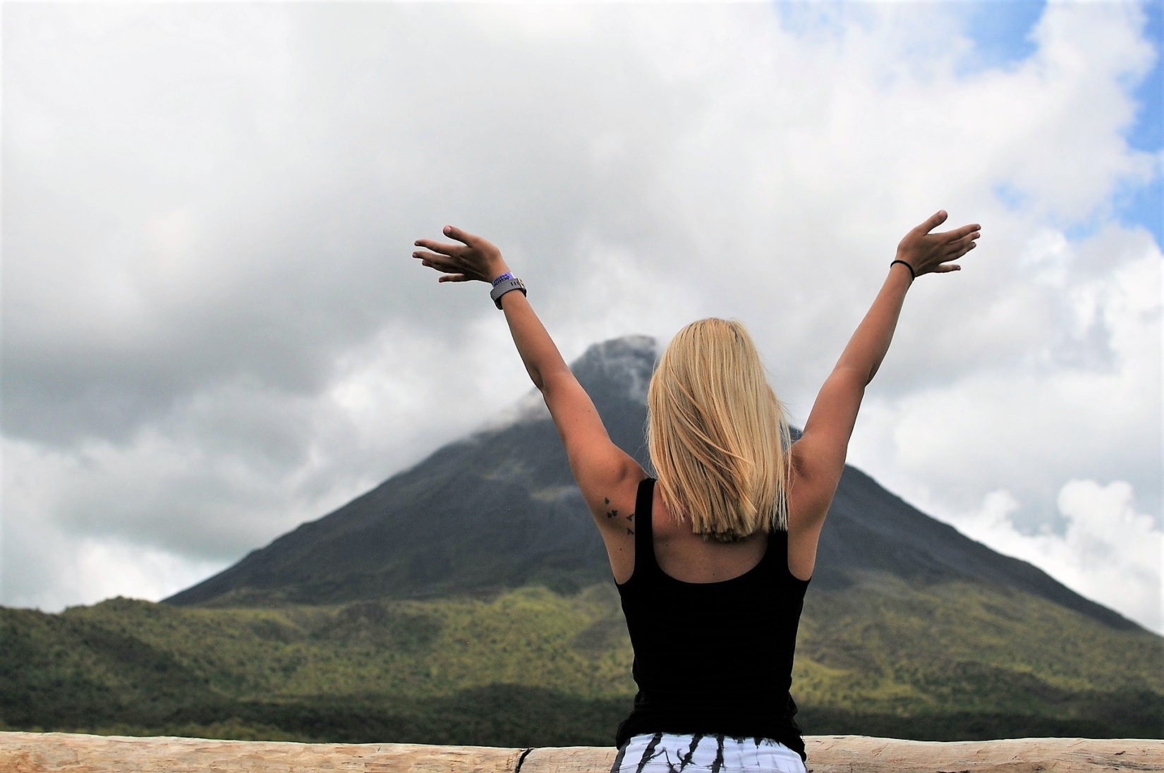 Woman opening her arms at the sight of the Arenal Volcano in Costa Rica