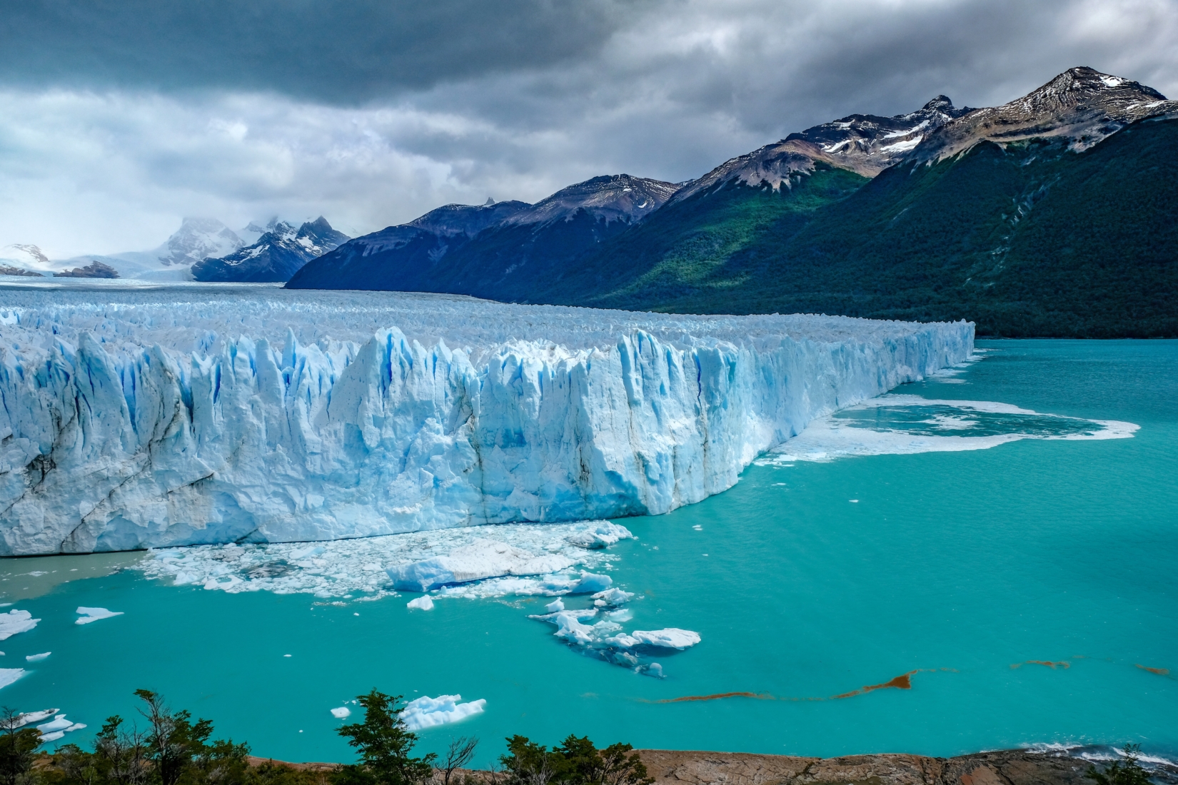 Large glacier in clear blue water with mountain in the background in Patagonia