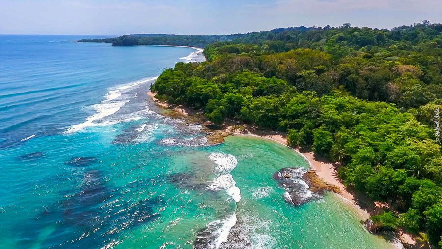 Waves crash on a stunning Costa Rican beach surrounded by lush rainforest