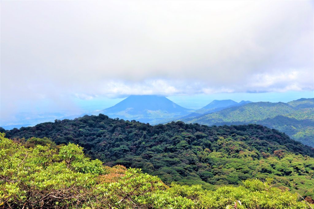 clouds hovering over dense forest of rolling hills and mountains in Monteverde