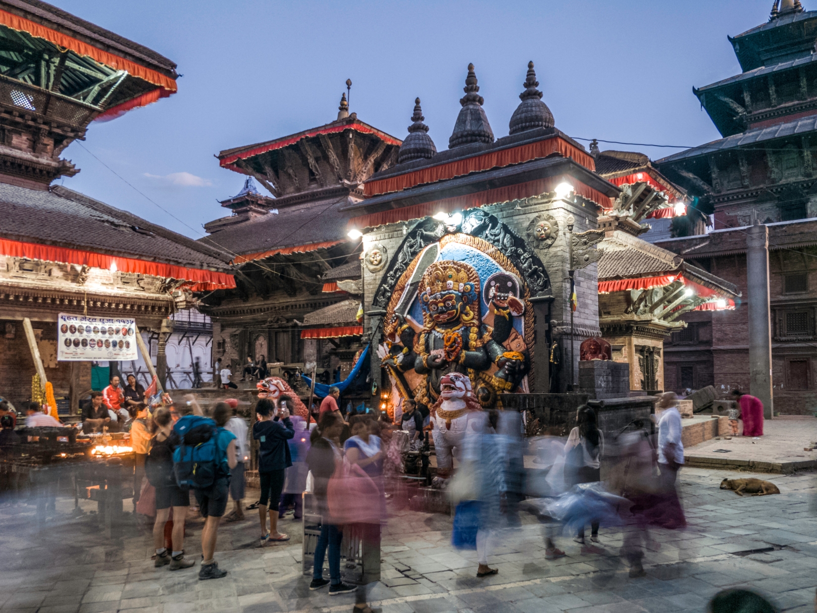 A photograph of a religious shrine in Kathmandu, with visitors and tourists surrounding it