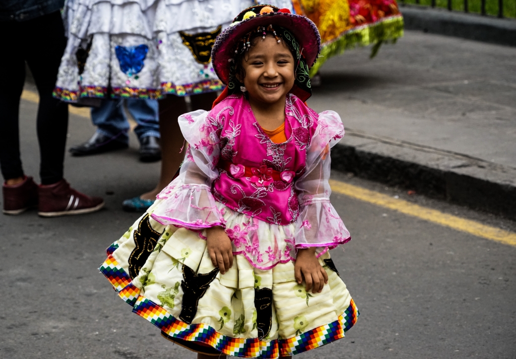 Young local girl in colorful dress and hat at the Virgen del Carmen Festival in Peru