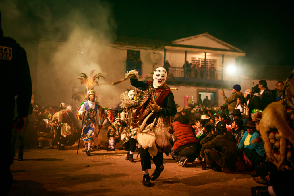 Costumed dancers moving through crowded street in Peru at night