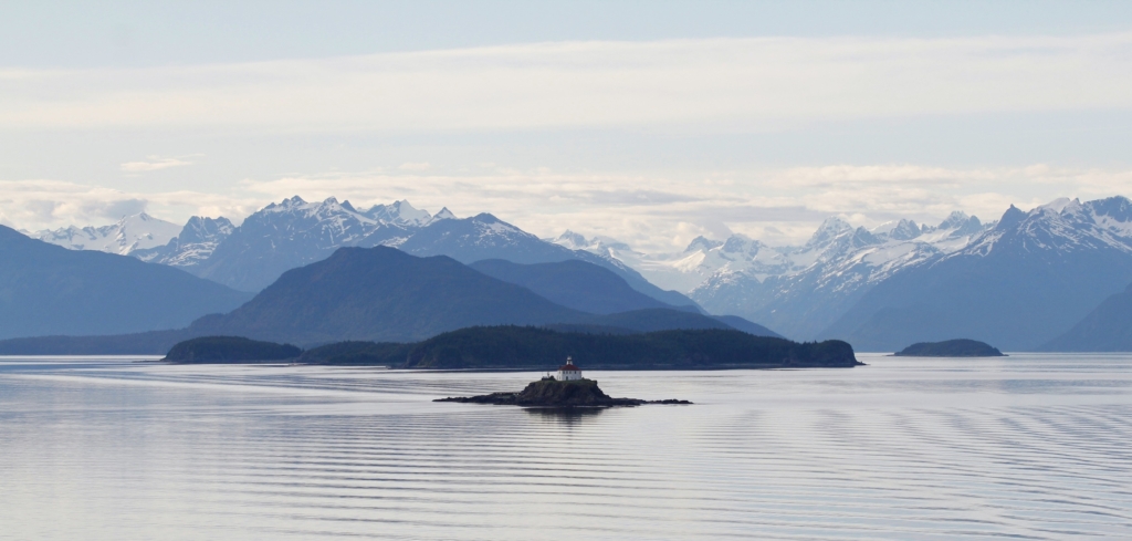 A lighthouse surrounded by water in Skagway against snowy mountainous landscape