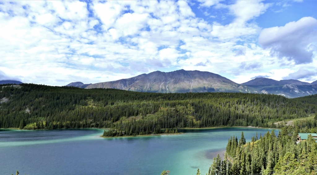 Clouds hanging over trees and mountains at Emerald Lake, an alpine lake in Whitehorse